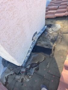 Chimney roof leak repair in Las Vegas showing damaged underlayment and flashing around a stucco chimney before replacement