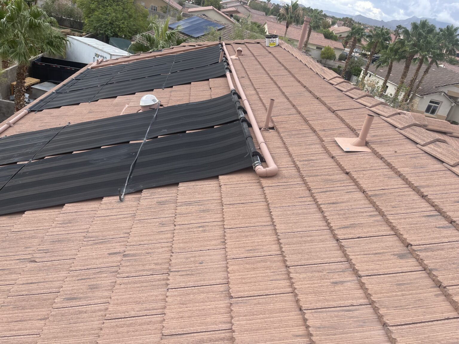 Pool solar panel roof repair assessment: black heating collectors and plumbing on a Las Vegas tile roof