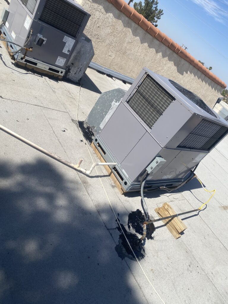 Two HVAC units, pipes, and sealed penetrations on a low-slope roof