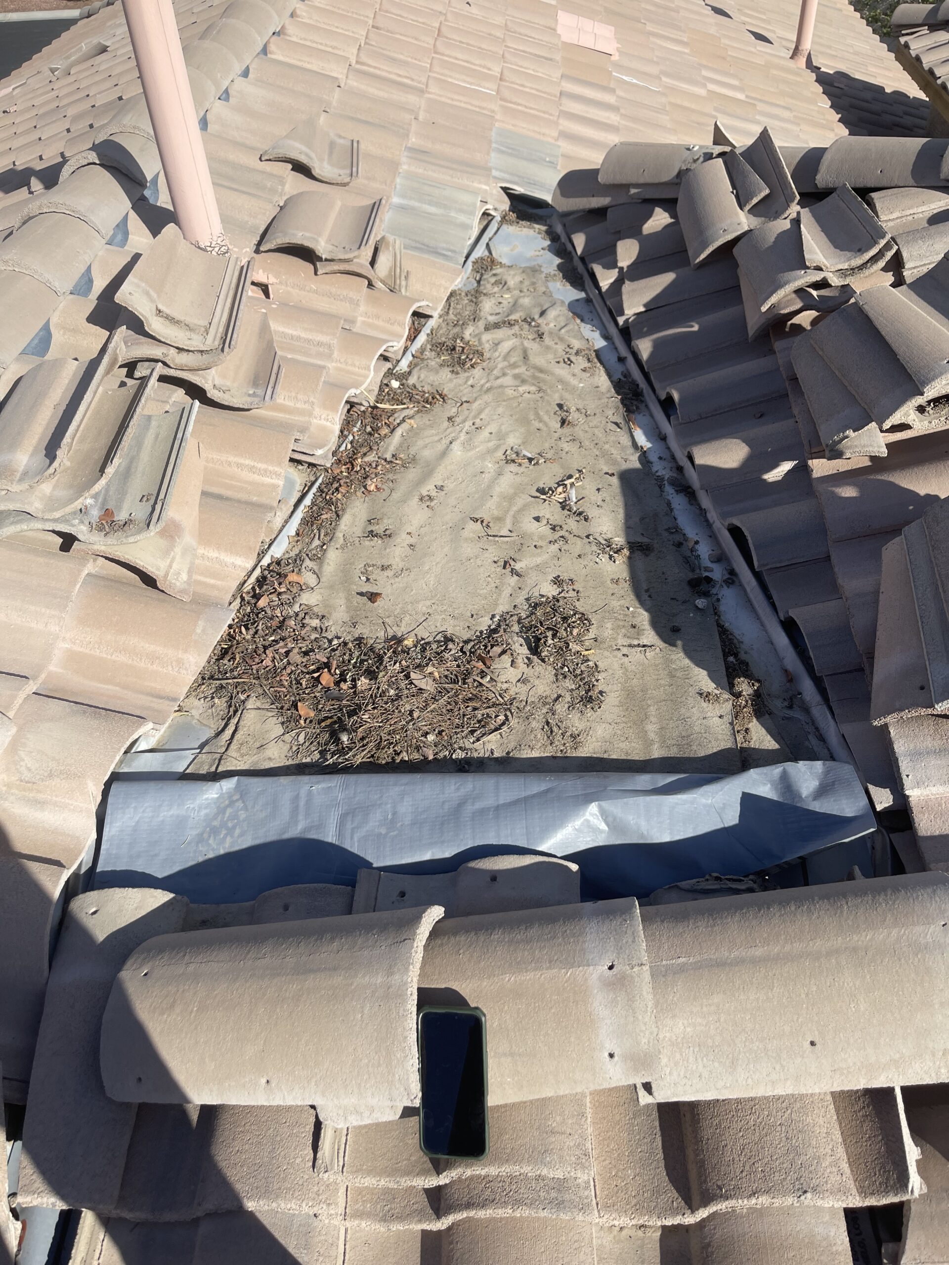 Tiles lifted to expose underlayment and debris during tile roof repair in Las Vegas 89131