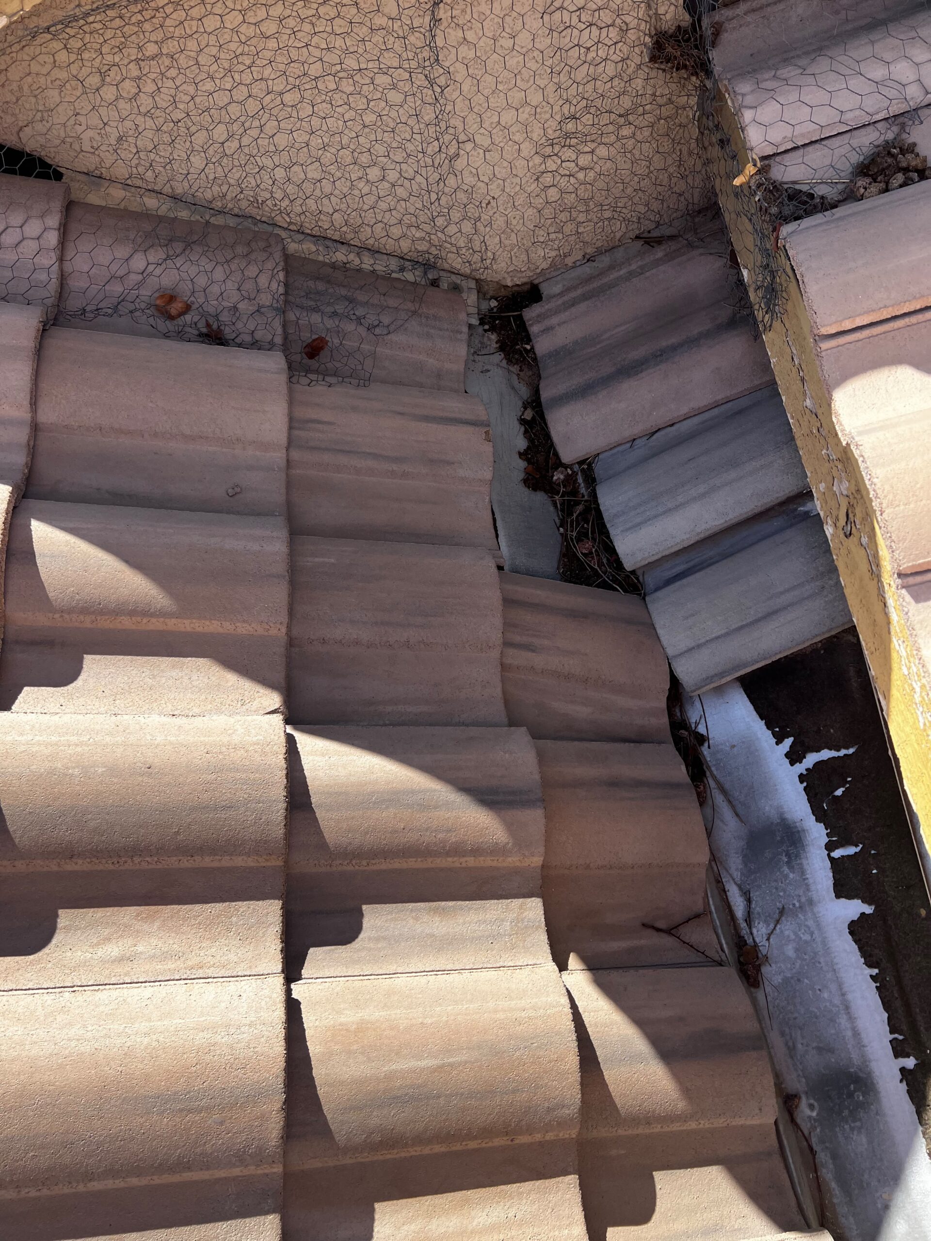 Tile roof junction with exposed metal flashing and bird mesh in Las Vegas 89131