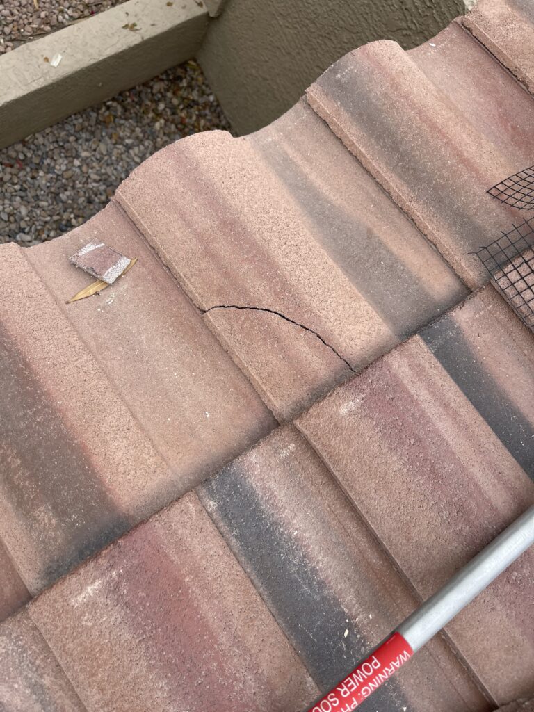 Close-up of a curved reddish roof tile with a visible crack