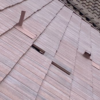 Flat roof tiles with visible gaps, a vent pipe, and a hooded vent