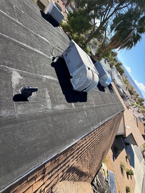 Dark low-slope roofing with rooftop equipment and adjacent shingle roofing