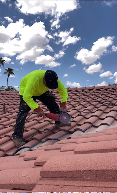 Roofer in a bright green shirt using a grinder on a curved roof tile