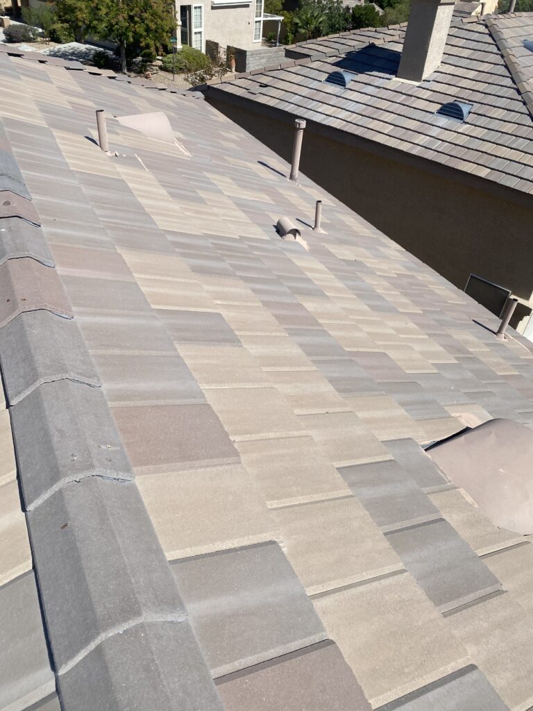 Multicolored flat roof tiles with ridge caps, pipe vents, and hooded roof vents