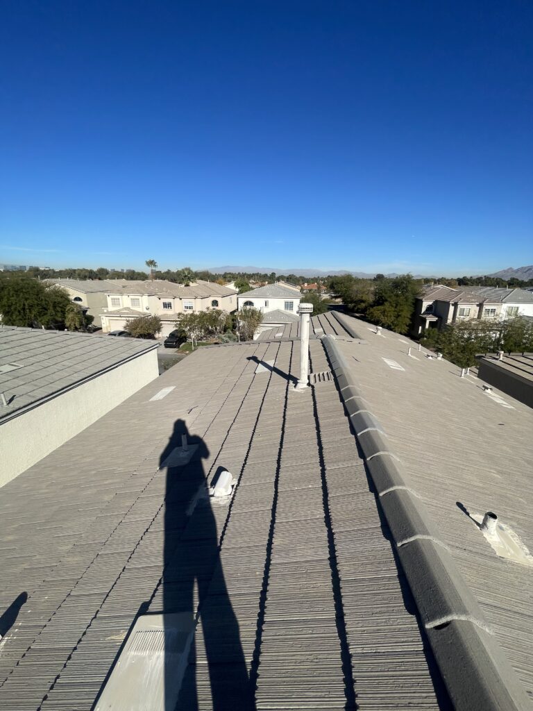 Gray tile roof with ridge caps, roof vents, and a metal vent pipe
