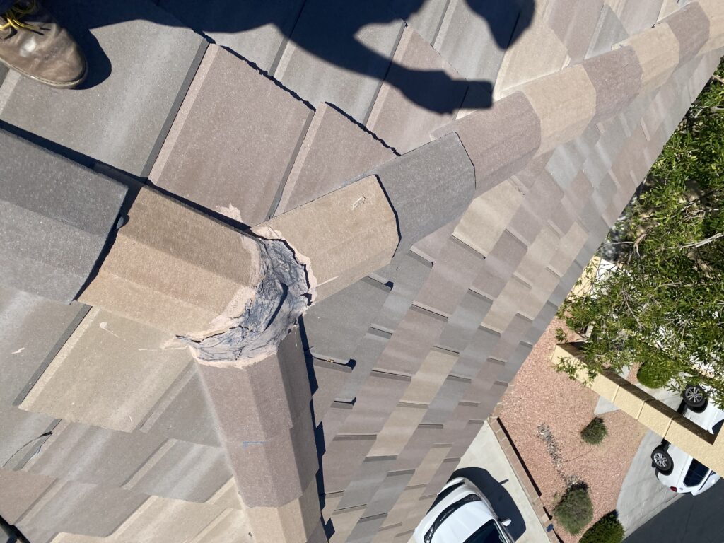 Tile roof ridge junction with chipped cap edges and dark sealant